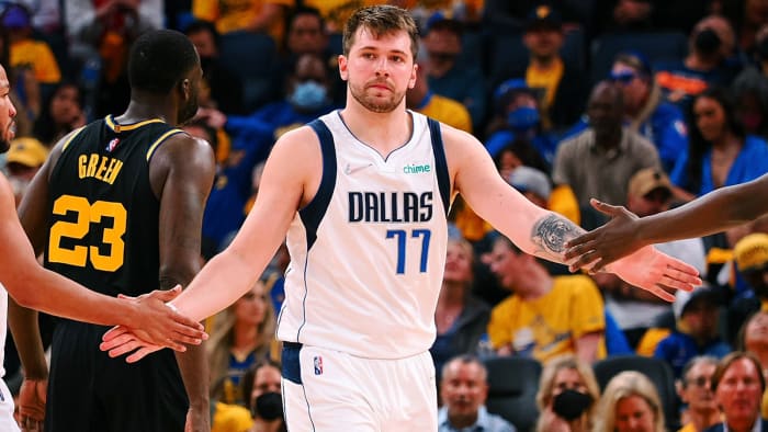 Dallas Mavericks guard Luka Doncic (center) high-fives guard Jalen Brunson after a play against the Golden State Warriors.